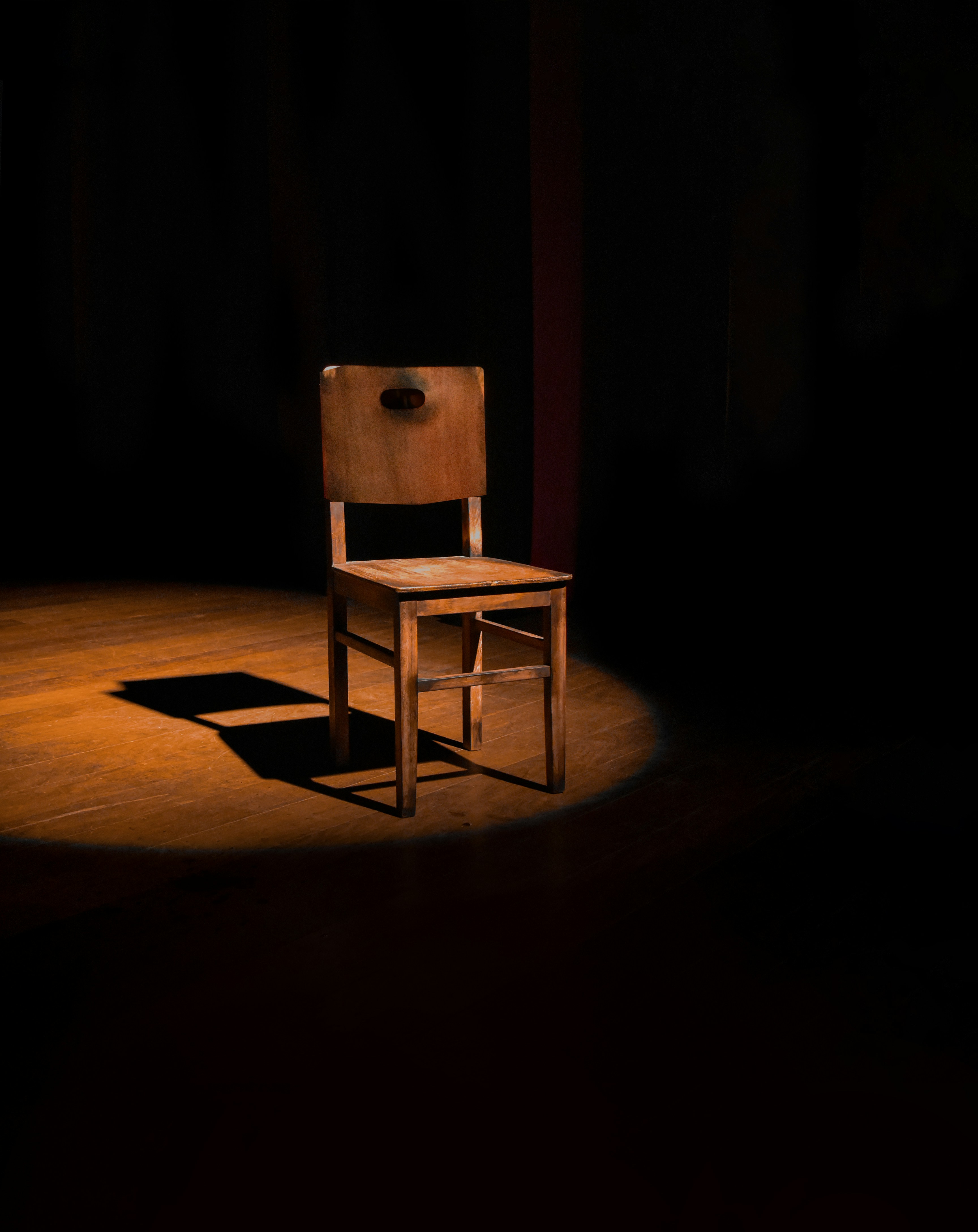 A wooden chair in a spotlight on stage