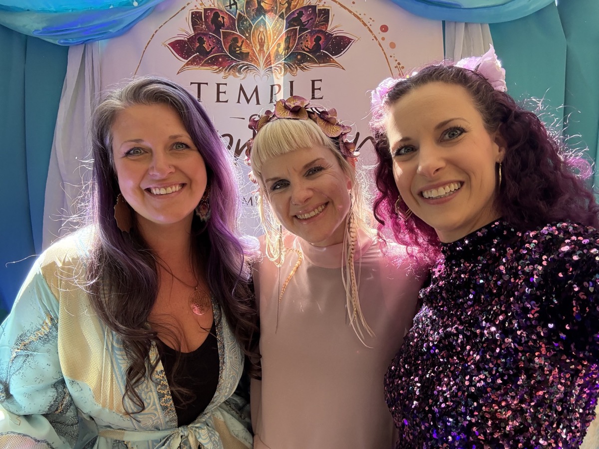 Three Temple of Expression hosts smiling together beneath the event banner