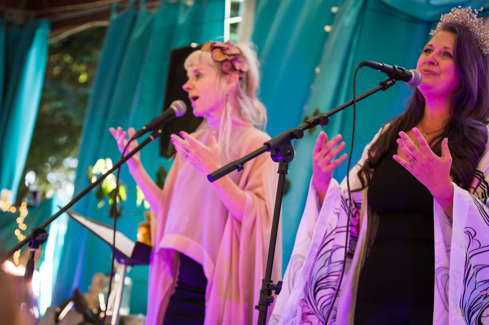Performers singing together against vibrant teal drapes